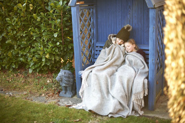 Geschwister in eine Decke gewickelt auf einer Laubenbank liegend - CUF05611