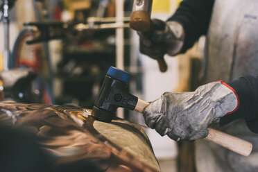 Hands of metalworker hammering copper in forge workshop - CUF05638