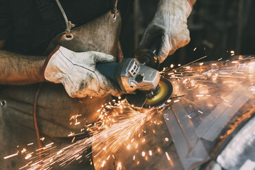 Hände eines Metallarbeiters beim Schleifen von Kupfer in einer Schmiedewerkstatt - CUF05640