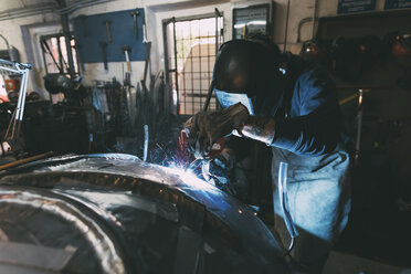 Metallarbeiter mit Schweißmaske beim Löten von Metall in der Schmiedewerkstatt - CUF05655
