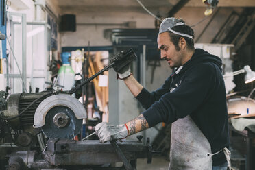 Metalworker using circular saw in forge workshop - CUF05663