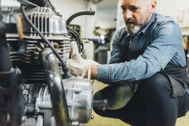 Älterer Mann, der in der Garage an einem Motorrad arbeitet - CUF05685