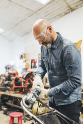 Mature man, working on motorcycle in garage - CUF05691