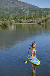 Rear view of young woman stand up paddleboarding on lake, Frisco, Colorado, USA - ISF01305