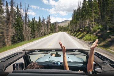 Road Trip Paar fahren Cabrio auf ländlichen Highway mit erhobenen Händen, Breckenridge, Colorado, USA - ISF01306