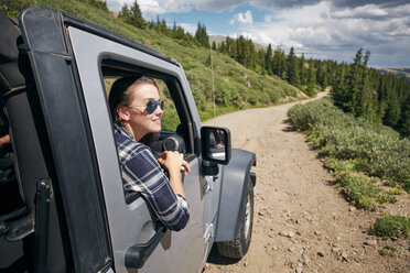 Young woman on road trip looking from car window in Rocky mountains, Breckenridge, Colorado, USA - ISF01314