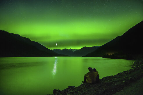 Pärchen sitzt am Lillooet Lake und beobachtet Nordlichter, Pemberton, British Columbia, Kanada - ISF01365