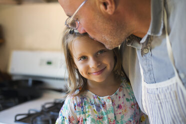 Portrait of girl being kissed on forehead by father in kitchen - ISF01376