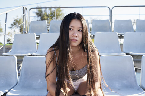Portrait of young woman sitting on grandstand of a stadium stock photo