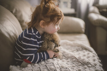 Junges Mädchen sitzt auf dem Sofa und umarmt ihren Hund - ISF01383