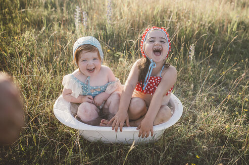 Zwei Mädchen auf einem Feld, die in einer Plastikwanne mit Wasser spielen - ISF01391