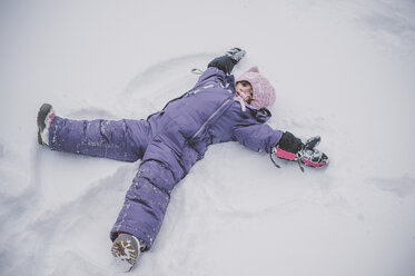 Young girl making snow angel in snow - ISF01392