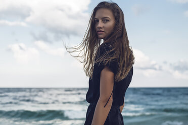 Porträt einer jungen Frau, die am Strand über ihre Schulter blickt, Odessa, Oblast Odessa, Ukraine - ISF01412