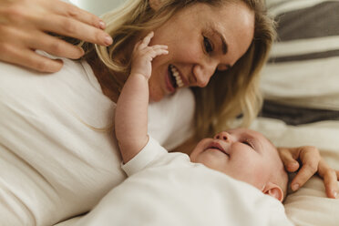 Woman lying on bed playing with baby daughter - ISF01429