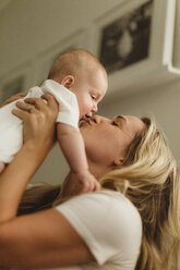 Frau hält ihre kleine Tochter hoch und küsst sie - ISF01435