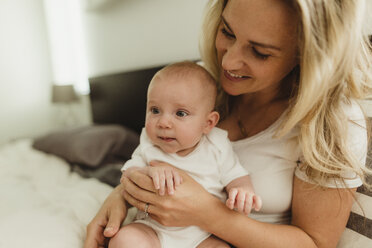 Kleines Mädchen sitzt auf dem Schoß der Mutter im Bett - ISF01439