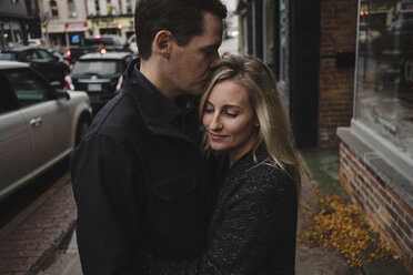 Mid adult couple hugging in street - ISF01448