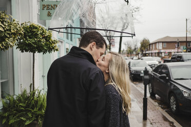 Mittleres erwachsenes Paar auf der Straße, küssend, Regenschirm haltend - ISF01449