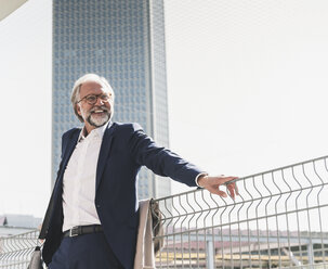 Happy mature businessman in the city looking around - UUF13654