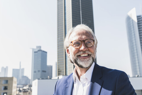 Portrait of happy mature businessman in the city looking around stock photo