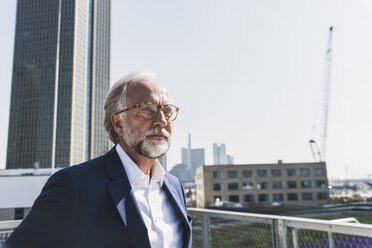 Serious mature businessman in the city looking around - UUF13658