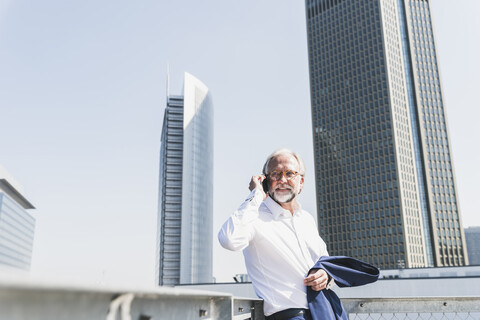 Confident mature businessman in the city on cell phone stock photo