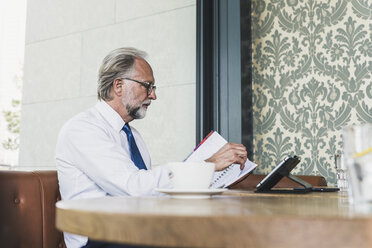 Reifer Geschäftsmann bei der Arbeit am Tisch in einem Cafe - UUF13683