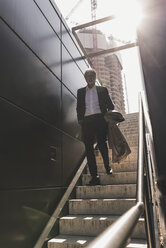 Mature businessman walking on staircase in the city - UUF13684