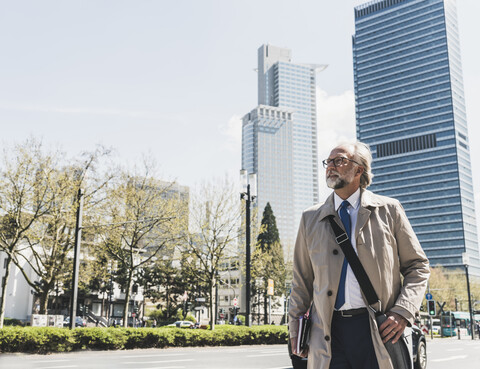 Confident mature businessman in the city looking around stock photo