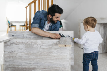 Father and daughter assembling a wooden table at home - JRFF01642