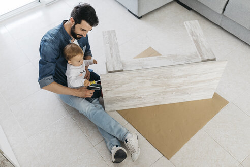 Father and daughter assembling a wooden table at home - JRFF01647