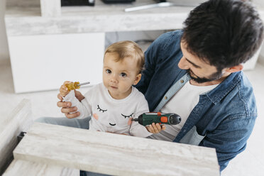 Father and daughter assembling a wooden table at home - JRFF01648