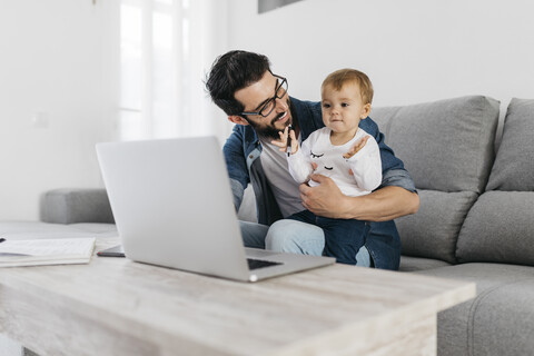 Father and daughter using laptop at home stock photo