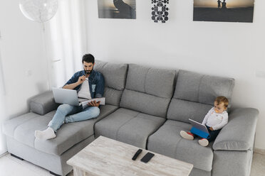 Father working in the living room while the daughter watching the tablet - JRFF01657