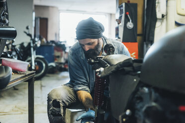 Älterer Mann, der in der Garage an einem Motorrad arbeitet - CUF05712