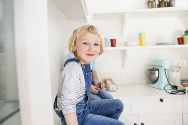 Porträt eines süßen Mädchens, das vor seinem Bruder auf dem Küchentisch sitzt - CUF05734
