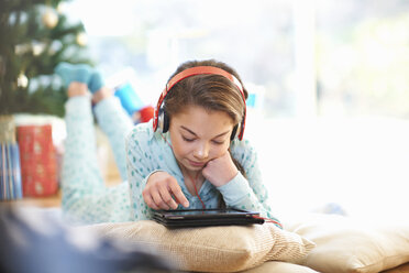 Girl lying on living room floor looking at digital tablet at christmas - CUF05738