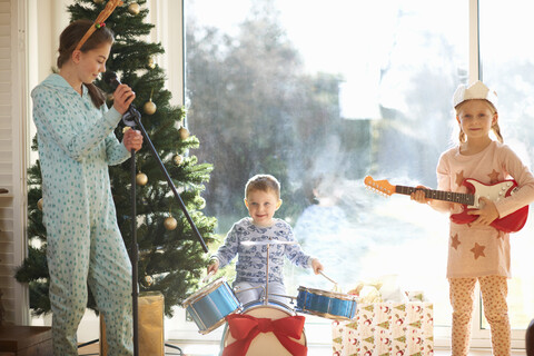 Junge und Schwestern spielen Spielzeug Schlagzeug und Gitarre am Weihnachtstag, lizenzfreies Stockfoto