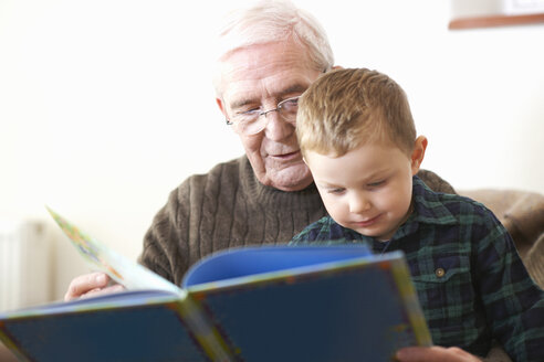 Älterer Mann liest seinem Enkel ein Buch vor - CUF05749