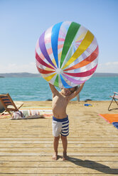 Junge hält Strandball auf dem Sonnendeck eines Hausbootes, Kraalbaai, Südafrika - CUF05852