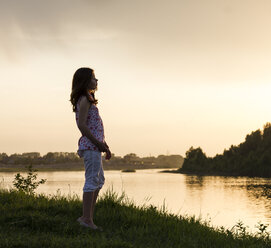 Teenage girl looking out over river at sunset - CUF05890