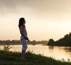 Teenager-Mädchen schaut bei Sonnenuntergang über den Fluss - CUF05890