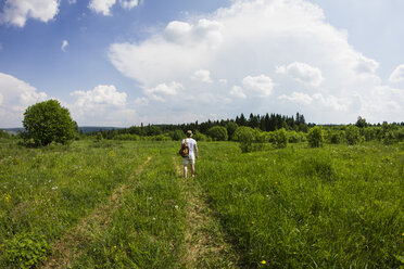 Rückansicht eines jungen männlichen Wanderers, der auf einem ländlichen Feldweg wandert - CUF05891