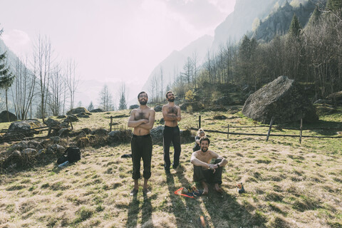 Vier erwachsene Freunde, die einen Mann beim Bouldern vom Tal aus beobachten, Lombardei, Italien, lizenzfreies Stockfoto