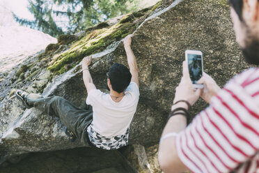 Männlicher Boulderer fotografiert Freund mit Smartphone, Lombardei, Italien - CUF05908