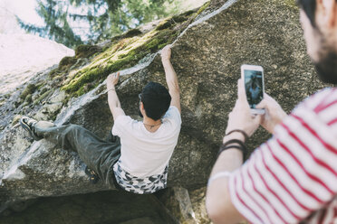 Male boulderer photographing friend with smartphone, Lombardy, Italy - CUF05908