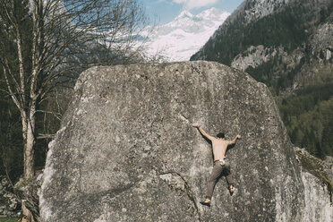 Rückansicht eines jungen männlichen Boulderers beim Klettern auf einen Felsblock, Lombardei, Italien - CUF05918