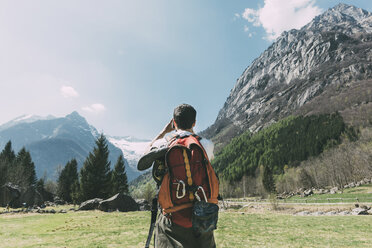 Rear view of male boulderer photographing mountains, Lombardy, Italy - CUF05925