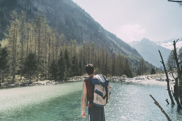 Rear view of male hiker looking out over mountain lake Lombardy, Italy - CUF05926