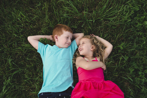 Overhead portrait of boy and sister lying on grass looking at each other - CUF05968